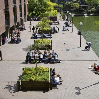 Lakeside terrace shot from above on a sunny day with students eating lunch and socialising outside